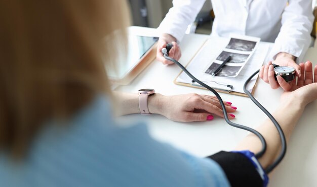 Photo un médecin gynécologue mesure la pression artérielle d'une jeune femme enceinte en gros plan à la clinique.