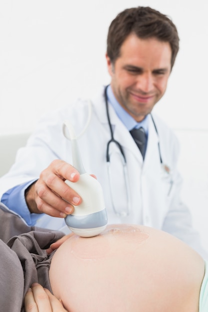 Médecin heureux faisant un balayage de sonogramme sur la femme enceinte