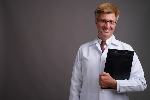 Médecin de l'homme aux cheveux blonds contre le mur gris