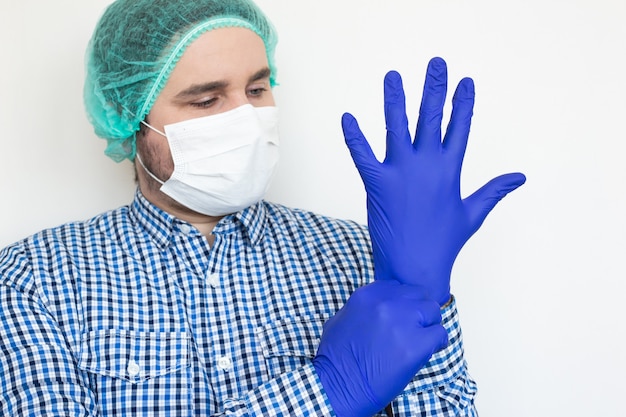 Médecin homme avec un masque mettant des gants.