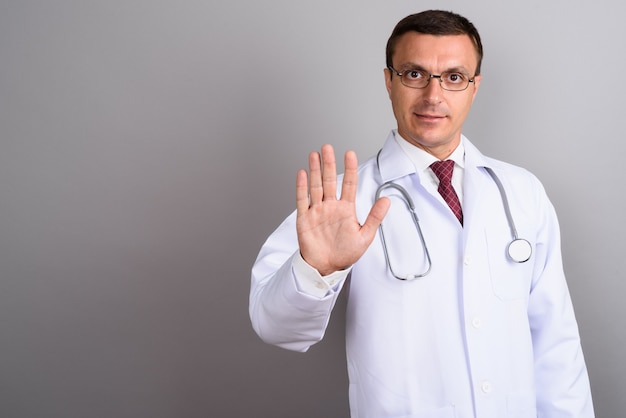 Médecin homme portant des lunettes contre le mur gris