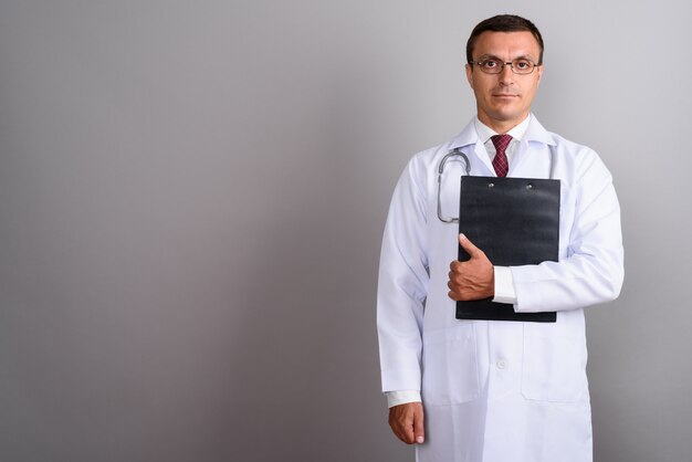 Médecin homme portant des lunettes contre le mur gris