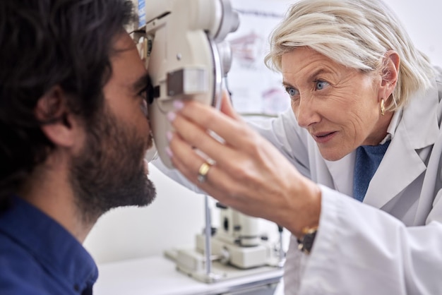 Médecin avec un homme en test de vision ou examen de la vue par un optométriste ou un ophtalmologiste senior concentré Opticien aidant à vérifier la santé de la rétine d'un client ou d'un client satisfait avec une assurance médicale