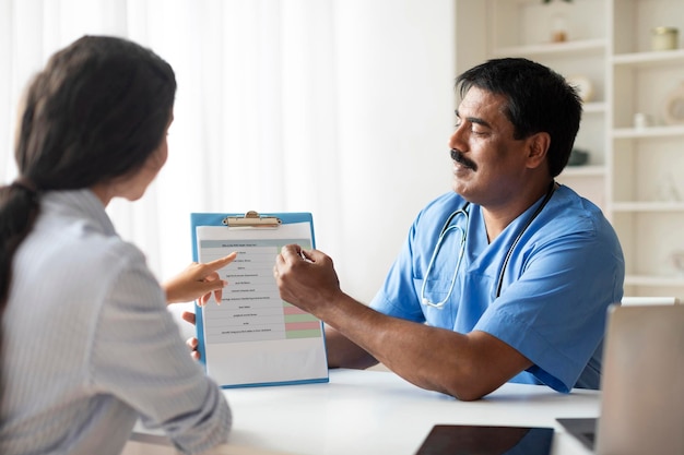 Photo un médecin indien mature consulte un patient avant un examen médical à la clinique.