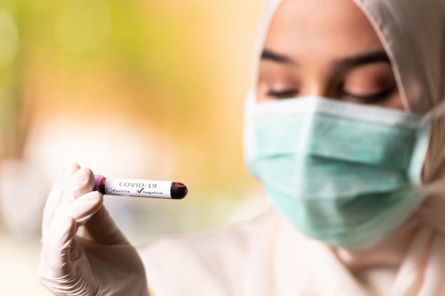 Médecin Infirmière Femme Musulmane Portant Un Masque De Protection Et Des Gants - Tenant Un Test De Sang Virus Négatif