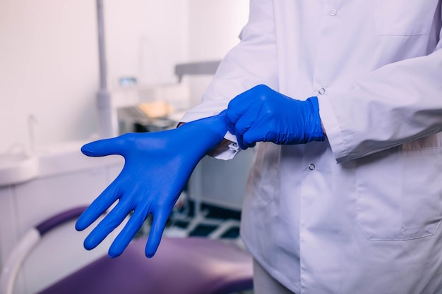 Médecin ou infirmière mettant des gants chirurgicaux bleus sécurité médicale professionnelle