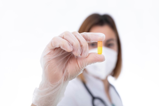 Médecin, infirmière et pharmacien regardant une pilule jaune.