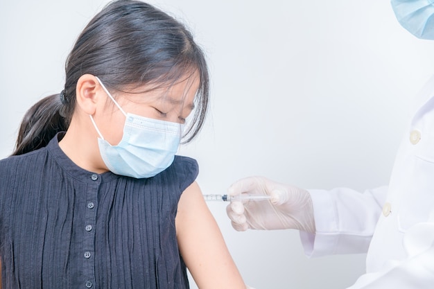 Médecin injectant la vaccination dans le bras d'une petite fille asiatique, médical sain et vaccin de lutte contre le concept de coronavirus