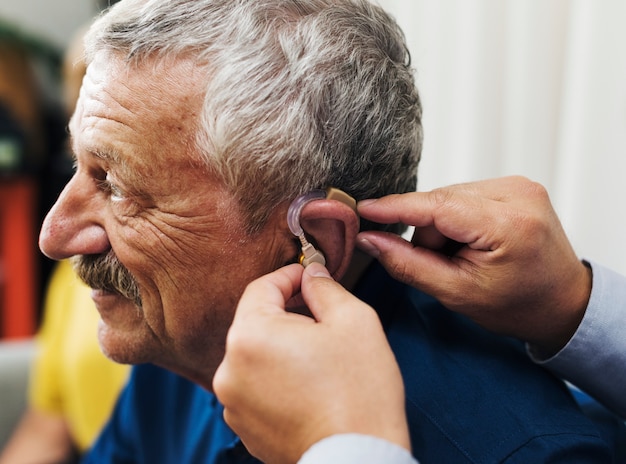 Photo un médecin insère un appareil auditif dans l'oreille du patient
