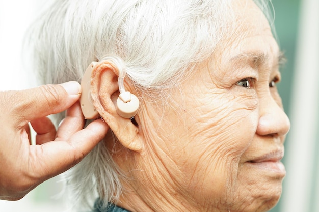 Le médecin installe une aide auditive à l'oreille d'un patient âgé pour réduire le problème de perte auditive