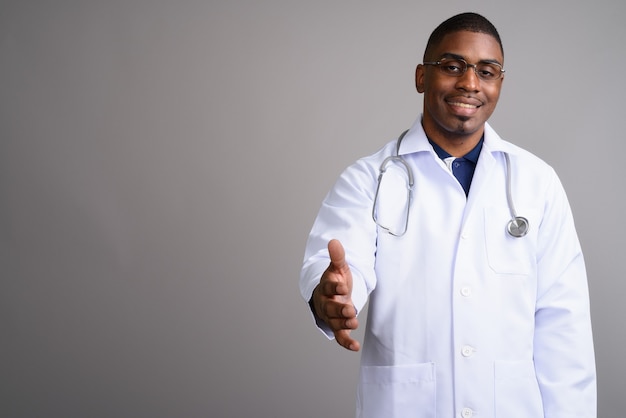 Médecin de jeune homme africain beau sur fond gris