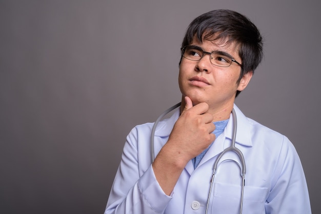 Médecin de jeune homme asiatique contre mur gris