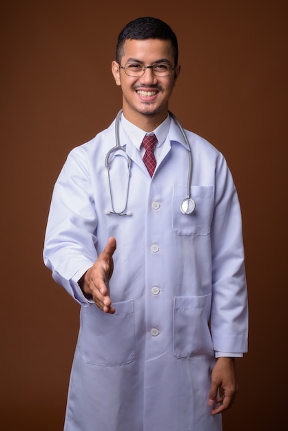 Médecin de jeune homme asiatique multiethnique contre mur marron