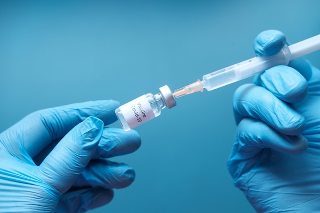 Médecin mains dans des gants médicaux détient une seringue et un vaccin