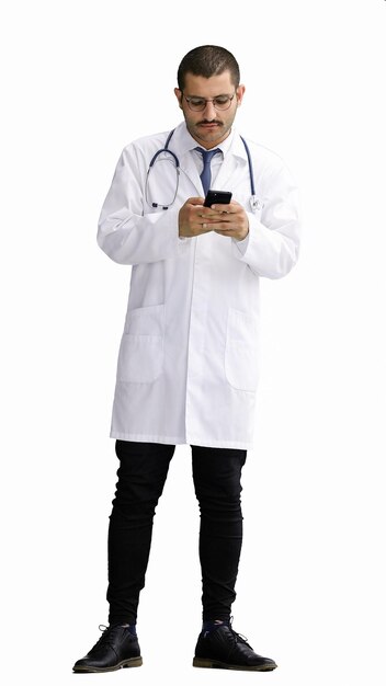 un médecin masculin dans un manteau blanc sur un fond blanc regardant le téléphone