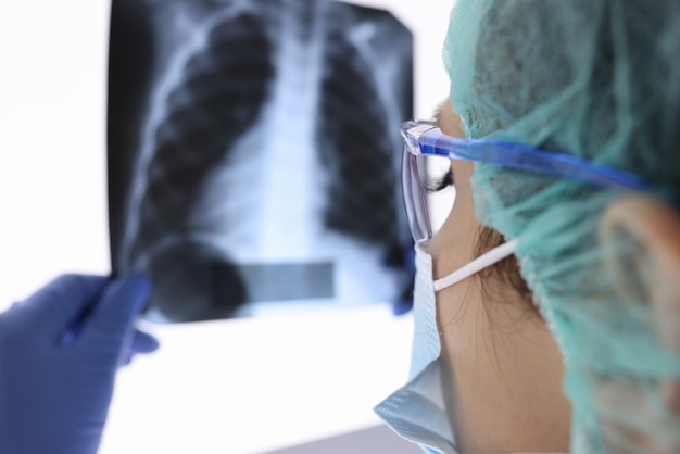 Médecin avec masque médical de protection et gants regarde une radiographie