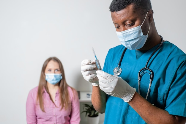 Médecin en masque médical tenant une seringue avec des médicaments