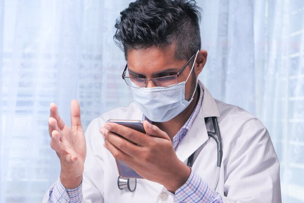 médecin en masque de protection à l'aide de smartphone à l'hôpital.