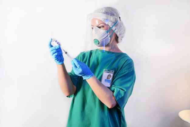 Médecin en masque de protection, gants en latex médical aspire un liquide médicinal dans la seringue