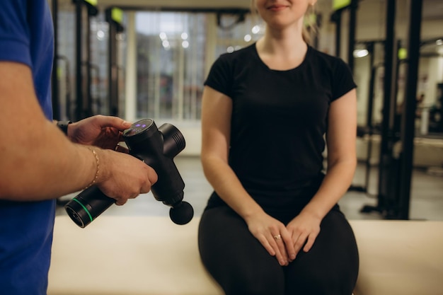 Un médecin massant le dos d'une patiente avec un pistolet de massage à percussion