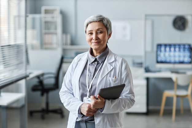 Une médecin mature heureuse avec une tablette devant la caméra.