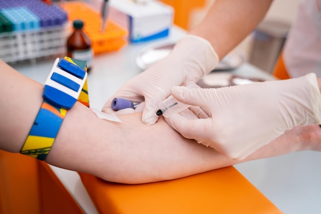 Un médecin méconnaissable avec une seringue prend du sang pour un test Mise au point sélective sur une partie d'un bras Arrière-plan de la clinique