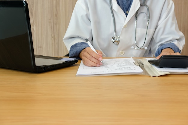 Un médecin médecin avec stéthoscope calcule les coûts et les revenus des frais médicaux.