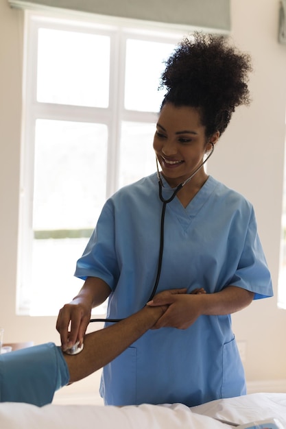 Une médecin mesure la pression artérielle d'un homme âgé dans la chambre.
