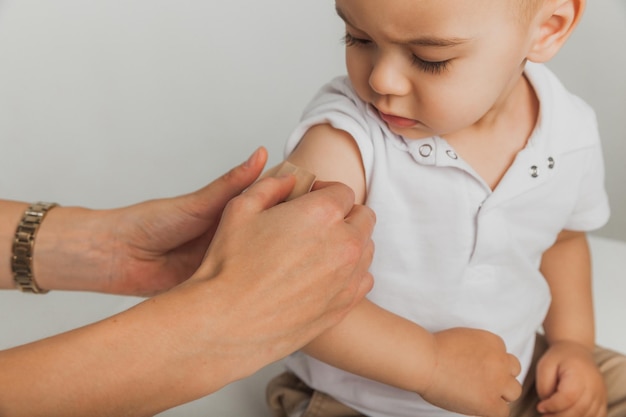 Le médecin met un patch sur l'épaule de l'enfant après avoir injecté le vaccin avec une seringue. Le patient reçoit les premiers soins. Fermer. Vaccination pour les enfants.