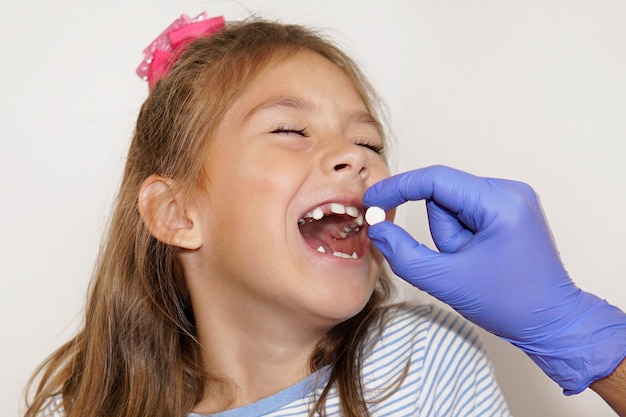 Le médecin met la pilule dans la bouche ouverte de l'enfant. une infirmière donne des médicaments à une petite fille souriante. Traitement des maladies à l'hôpital. La notion de santé