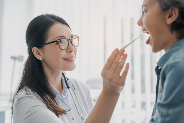 Photo une médecin mixte examine la bouche d'un garçon à la clinique.