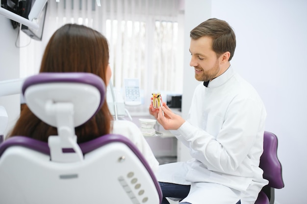 Le médecin montre sur un échantillon de dent en plastique ou modélise différentes méthodes de traitement des dents