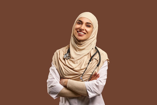 Médecin musulman portant un manteau blanc bras croisés debout et souriant Le concept médecine soins santé