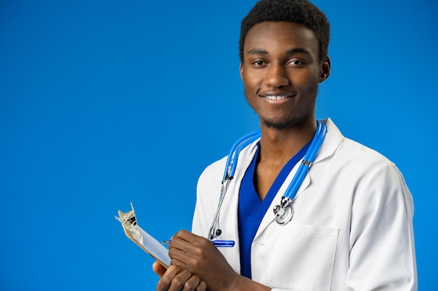 Médecin noir confiant posant sur fond de studio bleu