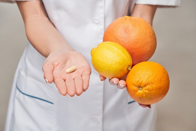 Médecin nutritionniste concept de mode de vie sain - tenant des agrumes biologiques frais - pamplemousse, orange, citron et capsules de vitamines