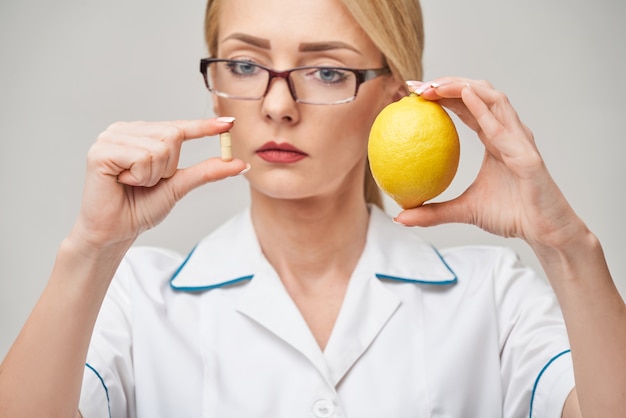 Médecin nutritionniste concept de mode de vie sain - tenant des capsules de vitamines et de fruits de citron bio