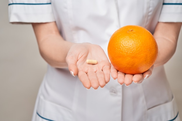 Médecin nutritionniste concept de mode de vie sain - tenant des capsules de vitamines ou des pilules de fruits orange et de nutrition