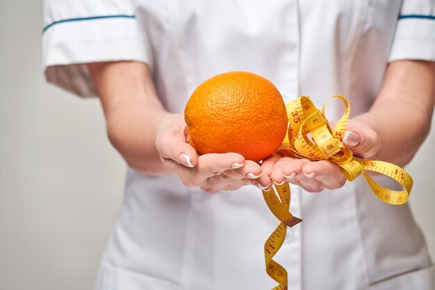 Médecin nutritionniste concept de mode de vie sain - tenant des fruits orange frais biologiques et ruban à mesurer