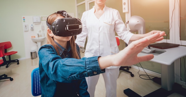 Un médecin en ophtalmologie vérifie la vision de la fille à l'aide de lunettes de réalité virtuelle.