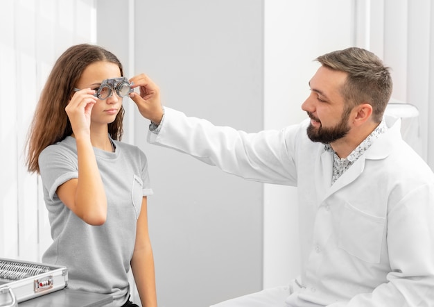 Médecin ophtalmologiste holding équipement examinant les yeux des filles adolescentes dans la clinique