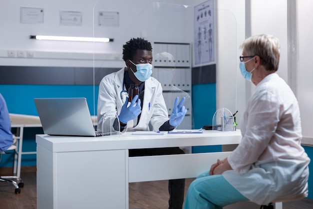 Médecin d'origine afro-américaine parlant à un vieux patient