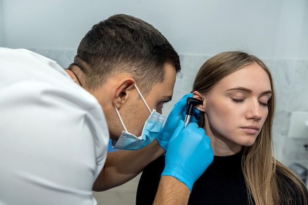 Photo un médecin orl examine l'oreille du patient à l'aide d'un otoscope