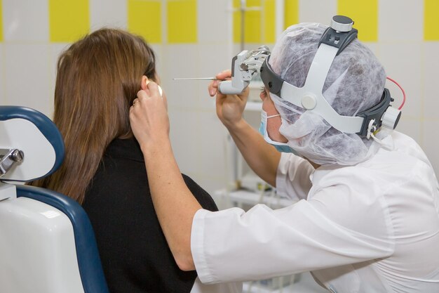 Le médecin ORL un oto-rhino-laryngologiste diagnostique l'oreille du patient Essuie l'otite moyenne ou le bouchon d'oreille