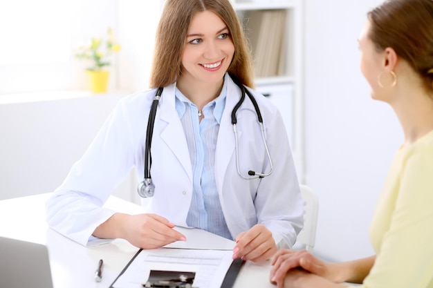 Médecin et patient assis au bureau près de la fenêtre, le soleil brille