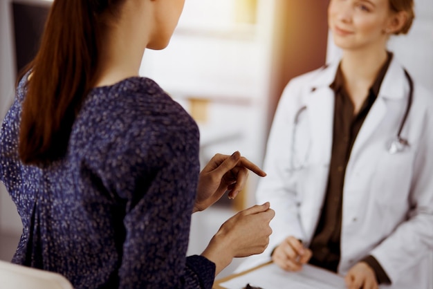 Médecin et patient discutant de l'examen de santé actuel alors qu'ils étaient assis dans une clinique ensoleillée. Service médical parfait à l'hôpital.