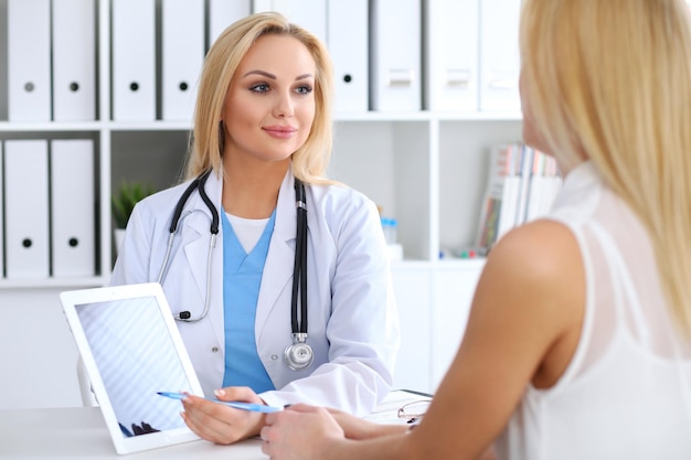 Médecin et patient discutant de quelque chose pendant que le médecin pointe vers l'ordinateur à tablette tactile