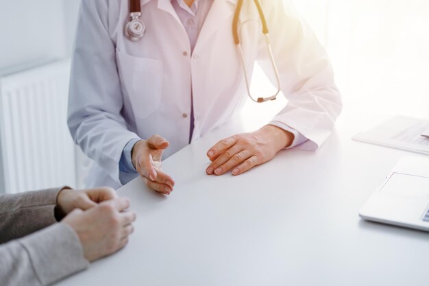 Médecin et patient discutant de questions de santé actuelles assis à la table du bureau de la clinique, seules les mains en gros plan. Notion de médecine