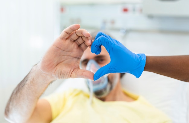 Médecin et patient en forme de coeur doigt portant un gant en latex jetable bleu