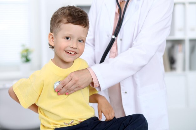 Médecin et patient à l'hôpital Heureux petit garçon s'amusant tout en étant examiné avec un stéthoscope Concept de soins de santé et d'assurance