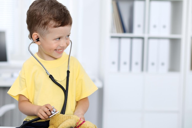 Médecin et patient à l'hôpital Heureux petit garçon s'amusant tout en étant examiné avec un stéthoscope Concept de soins de santé et d'assurance